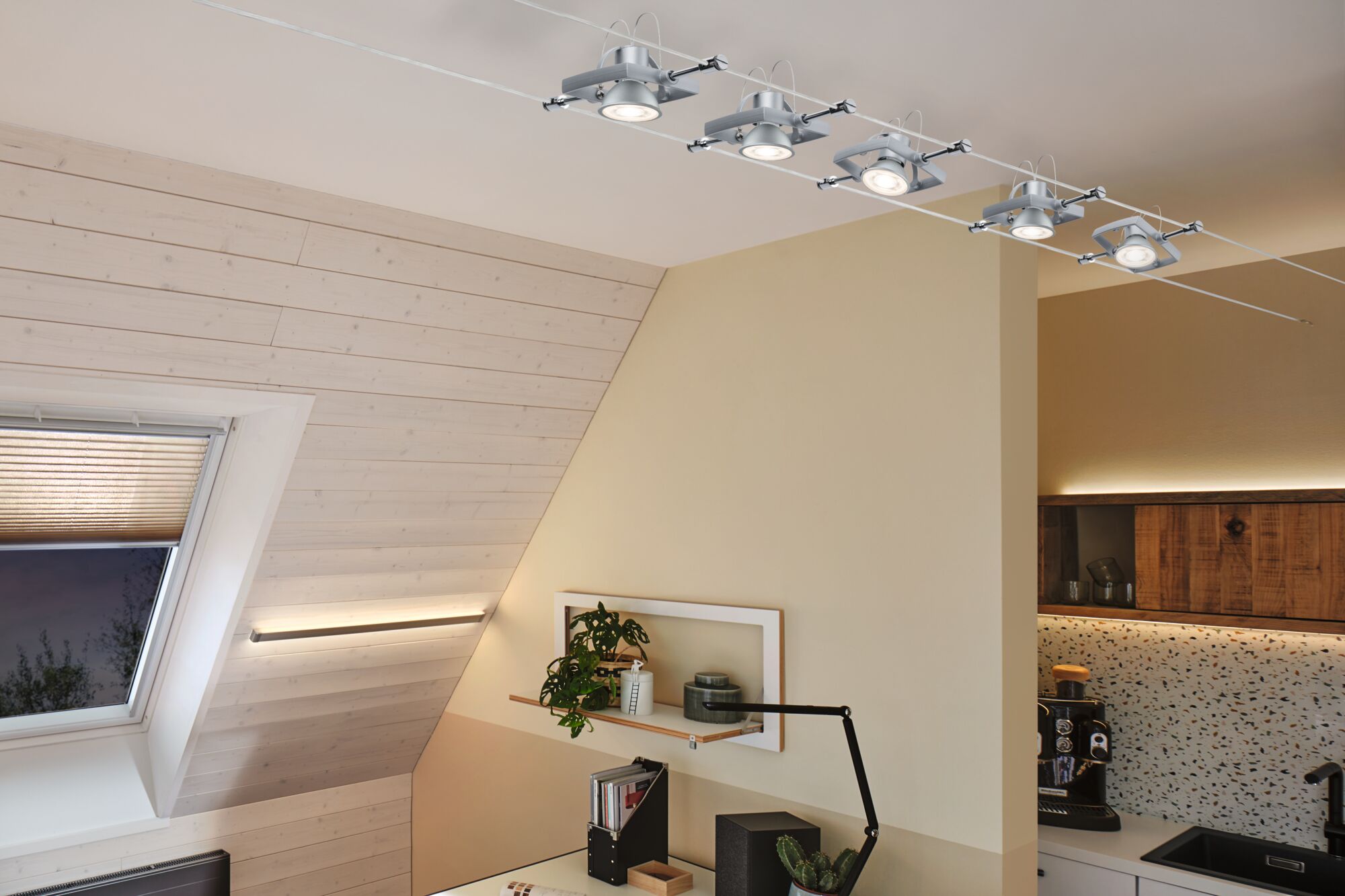 Moderne kabelspot med fem sølvfarvede LED-lamper i hyggeligt opholdsrum med ovenlysvindue.