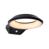 Black LED wall light with round warm white illumination and motion sensor for outdoor use.