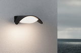 Modern black outdoor wall light with white diffuser on grey wall, ideal for garden lighting solutions.