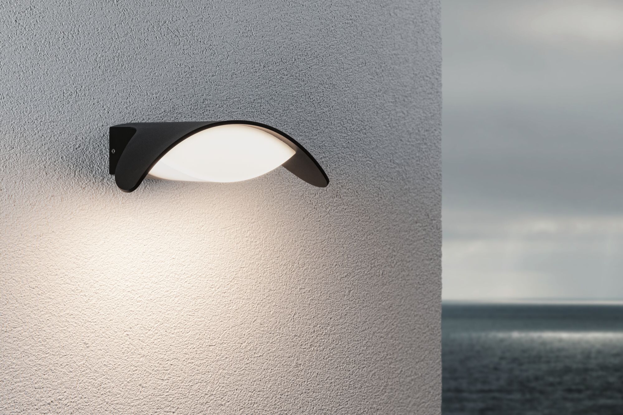 Moderne schwarze Außenwandleuchte mit weißem Diffusor an grauer Wand, geeignet für Gartenbeleuchtung.