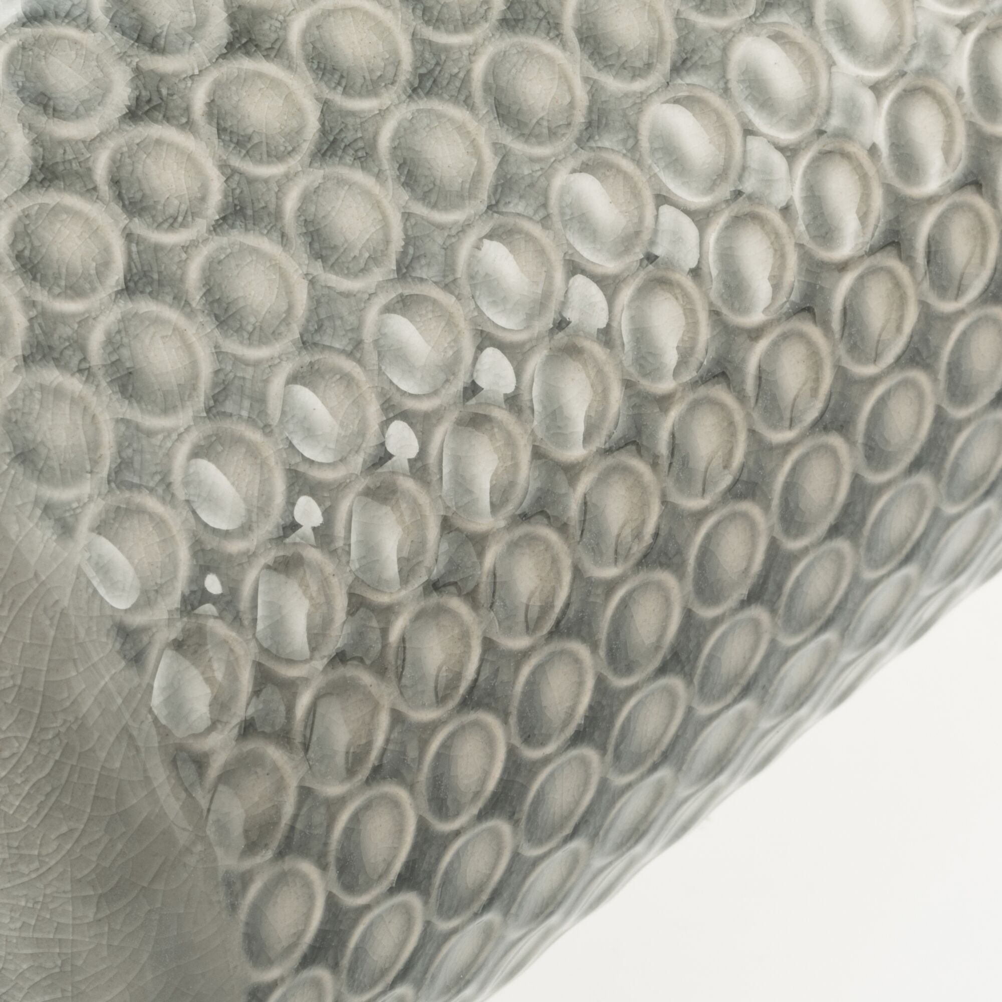 Close-up of grey ceramic surface with raised round patterns and glossy finish for home decor