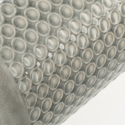 Gros plan sur une surface en céramique grise avec motifs ronds en relief et finition brillante