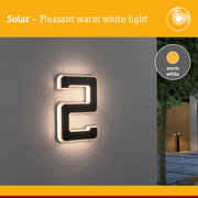 Solar-powered house number with warm white light mounted on grey wall for outdoor lighting