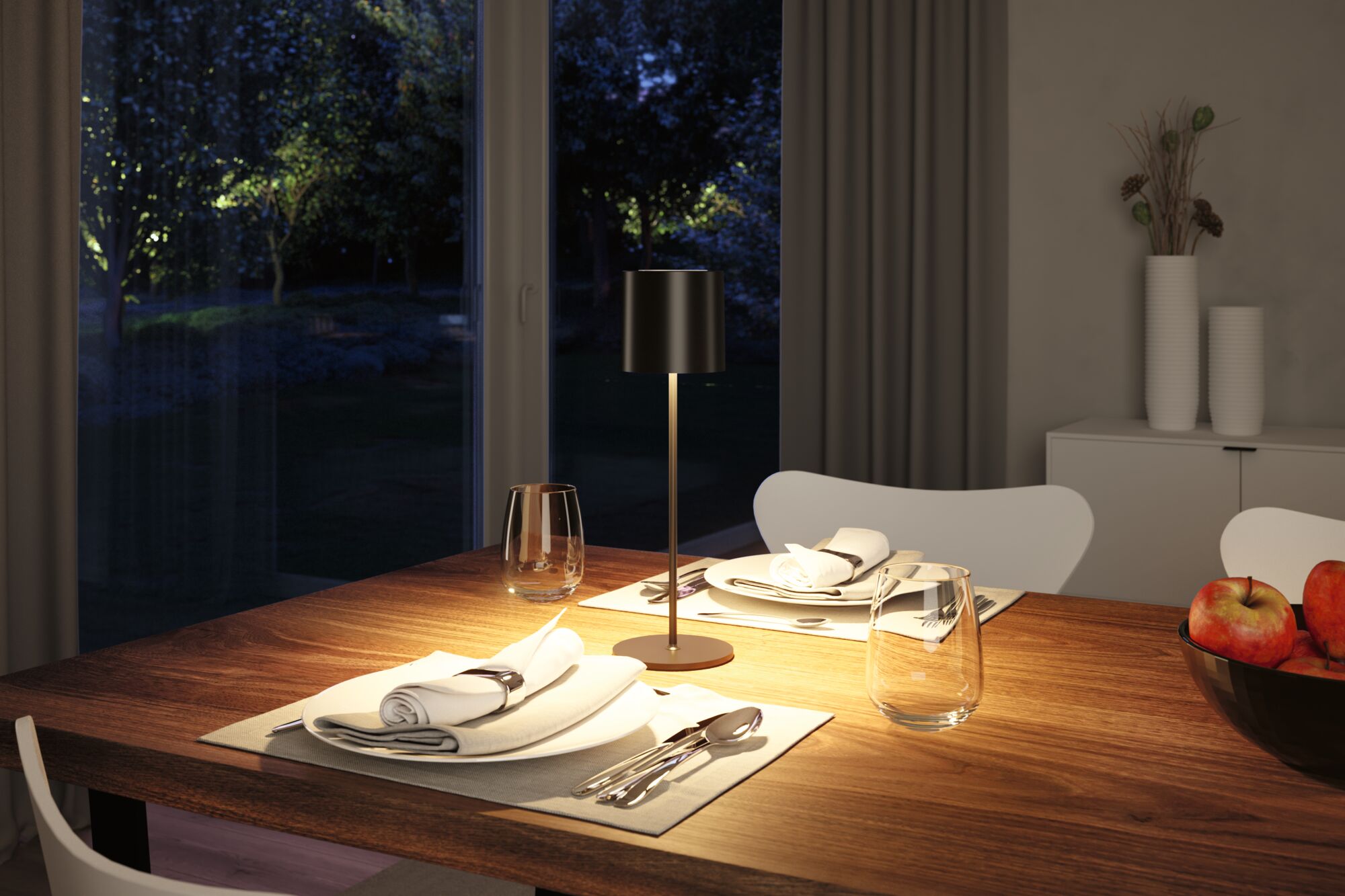 Modern black metal table lamp on wooden dining table with set places and apples