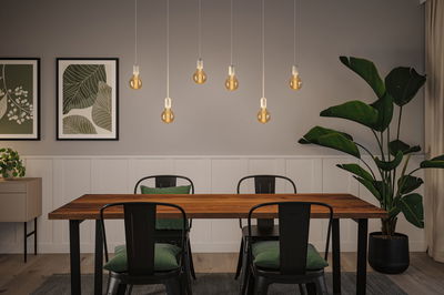 Moderner Essbereich mit Holz-Tisch, schwarzen Metallstühlen und warmen LED-Glühbirnen als Pendelleuchten