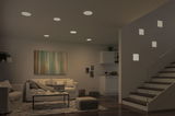 Modern living room with white LED recessed lights and square wall lamps by staircase, wooden flooring
