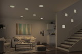 Modern living room with white LED recessed lights and square wall lamps by staircase, wooden flooring