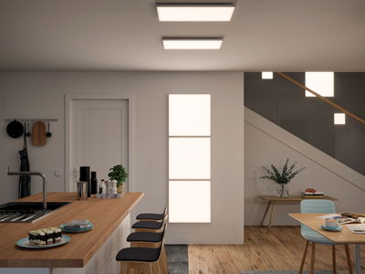 Modern kitchen with wooden countertop and three black bar stools, lit by rectangular LED ceiling lights