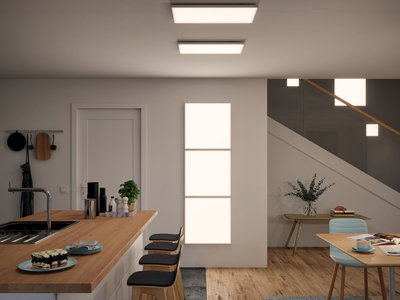 Moderne keuken met houten aanrecht en drie zwarte barkrukken, verlicht door rechthoekige LED-plafondlampen