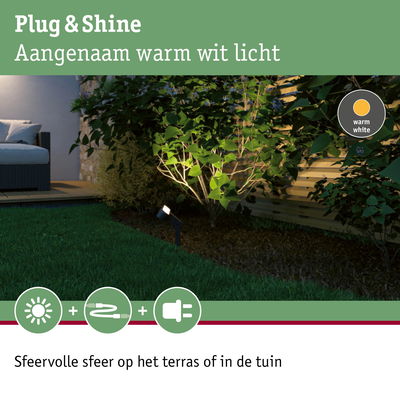 Buitenlamp met warm wit licht verlicht groene planten bij houten schutting in tuin