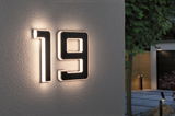 Illuminated house number 19 in black material with warm white LED light on exterior wall.