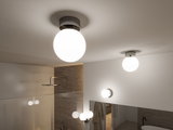Round ceiling light with white glass and grey metal mount in modern bathroom with mirror.