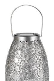 Zilveren metalen lantaarn met fijn patroon en zonnepaneel bovenop voor buitenverlichting