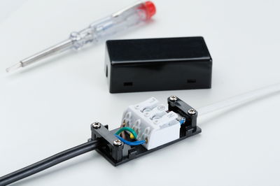 Electrical connection box with black and white cables, screwdriver in background for lighting installation