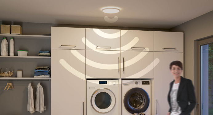 Panneau LED rond blanc éclairant une buanderie moderne avec lave-linge et sèche-linge.