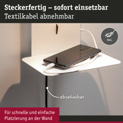 Weiße Wandhalterung mit abnehmbarem Textilkabel und Smartphone zum Laden auf weißem Regal