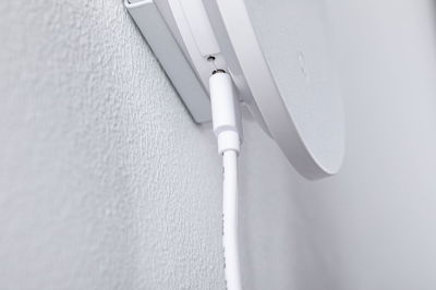 Close-up of white cable connection on white wall mount for electronic device installation