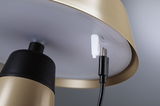 Nahaufnahme eines goldfarbenen Metalllampenschirms mit USB-C-Ladekabelanschluss und schwarzem Kabel