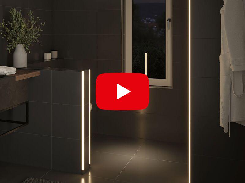 Modern bathroom with warm white LED light strips on black tiled walls for ambient lighting effect