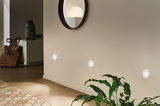Trois veilleuses LED blanches rondes sur mur dans couloir moderne avec sol en bois et plante