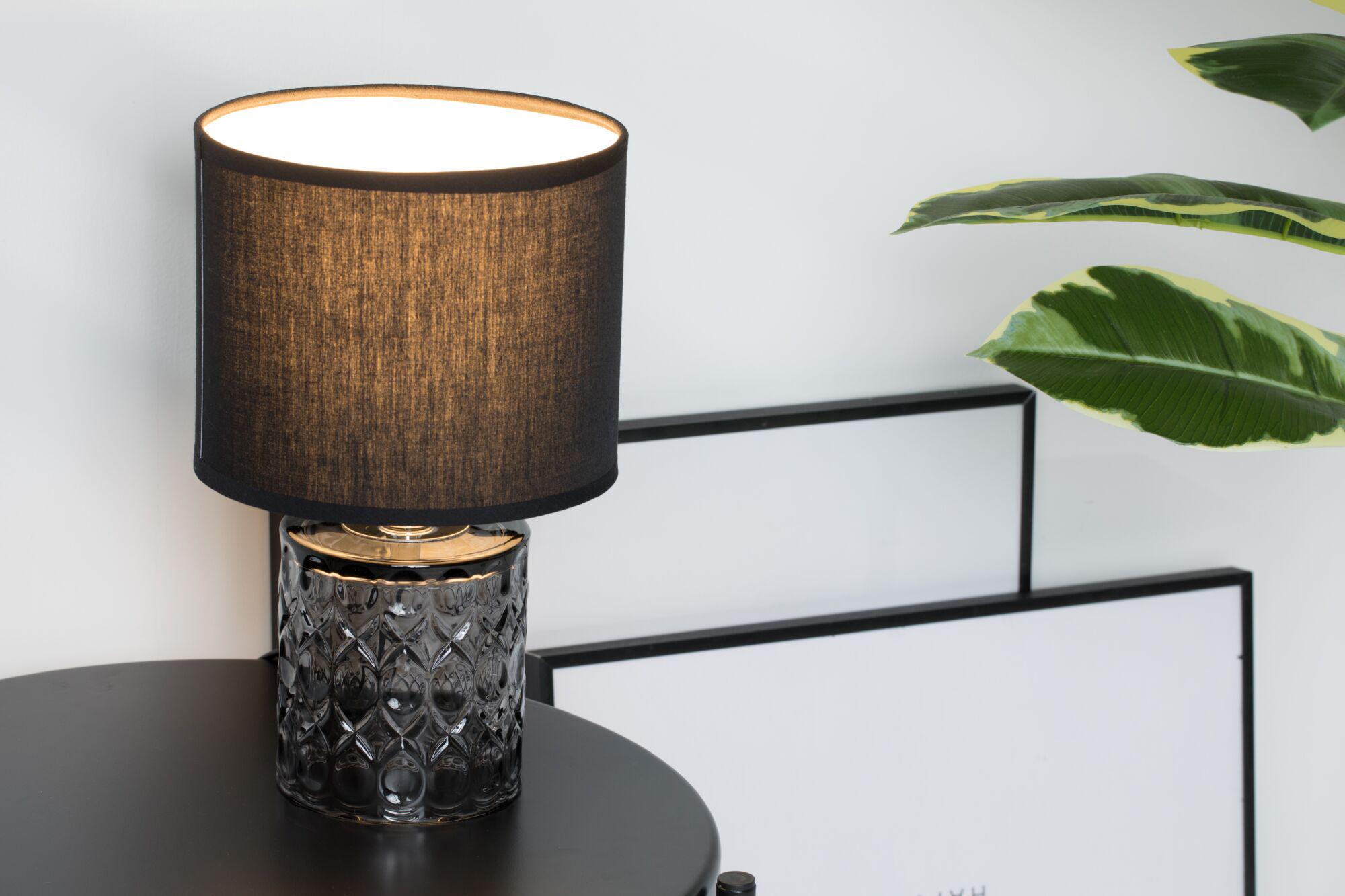 Moderne tafellamp met zwarte stoffen kap en patroon glazen voet voor stijlvolle woonverlichting
