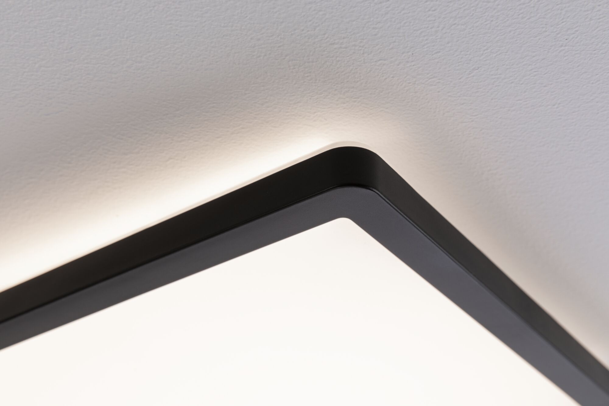 Black square LED ceiling light with indirect glow on white ceiling, modern lighting fixture