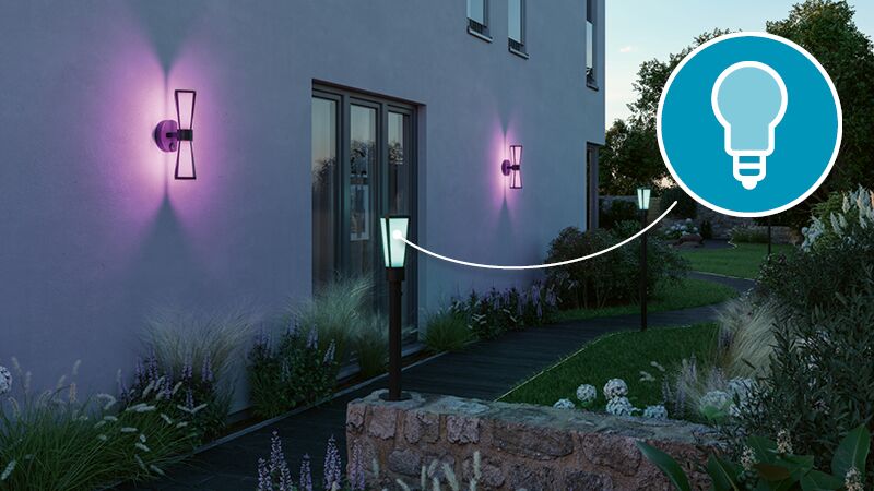 Modern outdoor wall lights with purple glow on house wall and garden path lighting at dusk