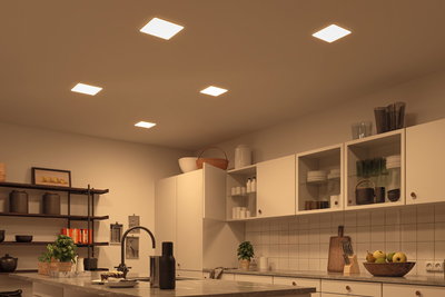 Cuisine moderne avec armoires blanches et éclairage LED blanc chaud au plafond, éclairage économe en énergie.