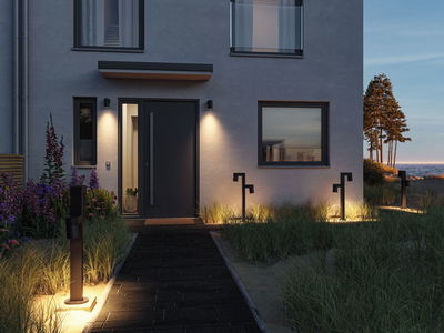 Moderne udendørsbelysning med sorte LED-sti- og væglamper på hus med grå facade.