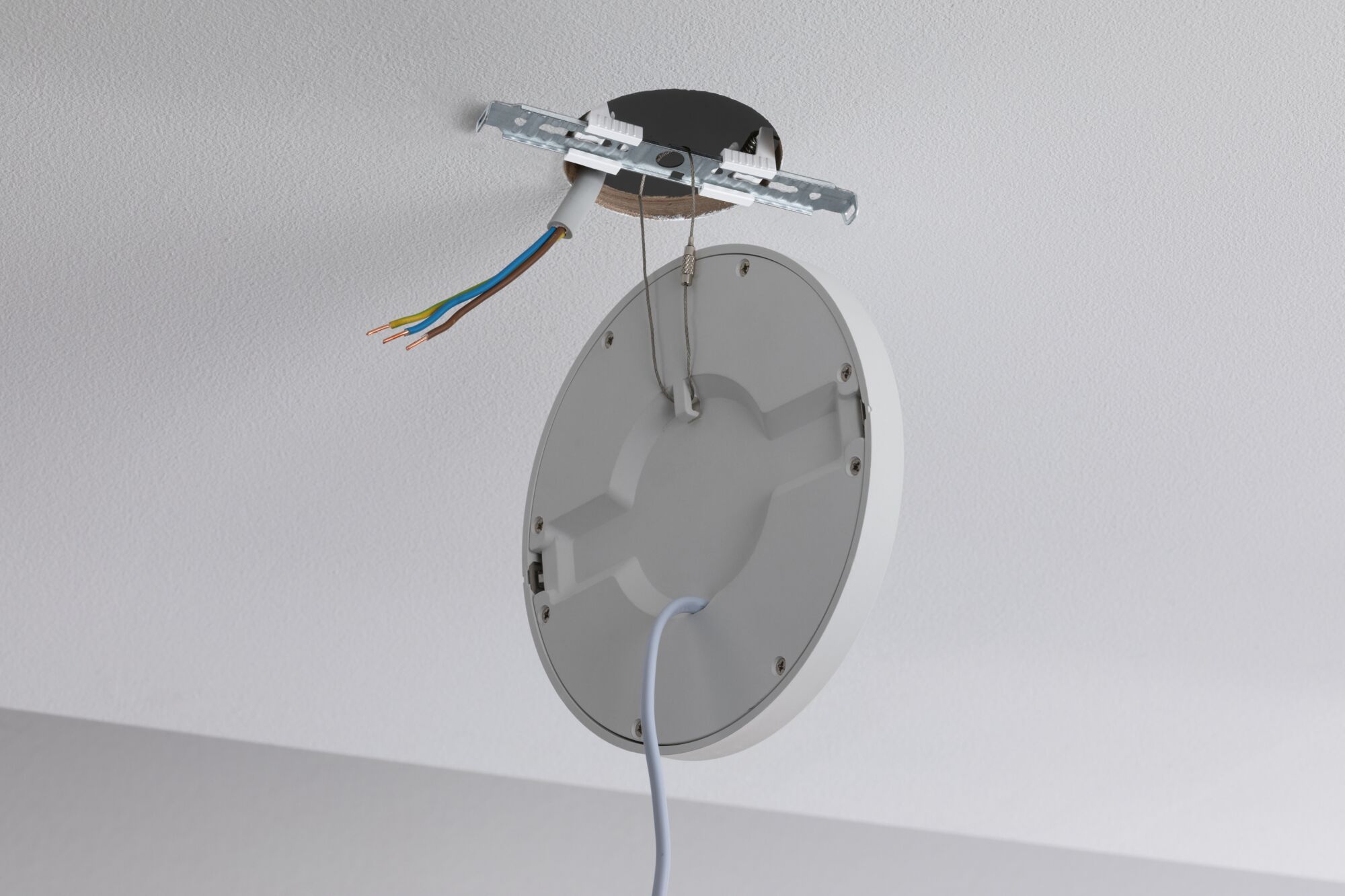 Round white ceiling mount with cables and metal bracket for LED light installation.