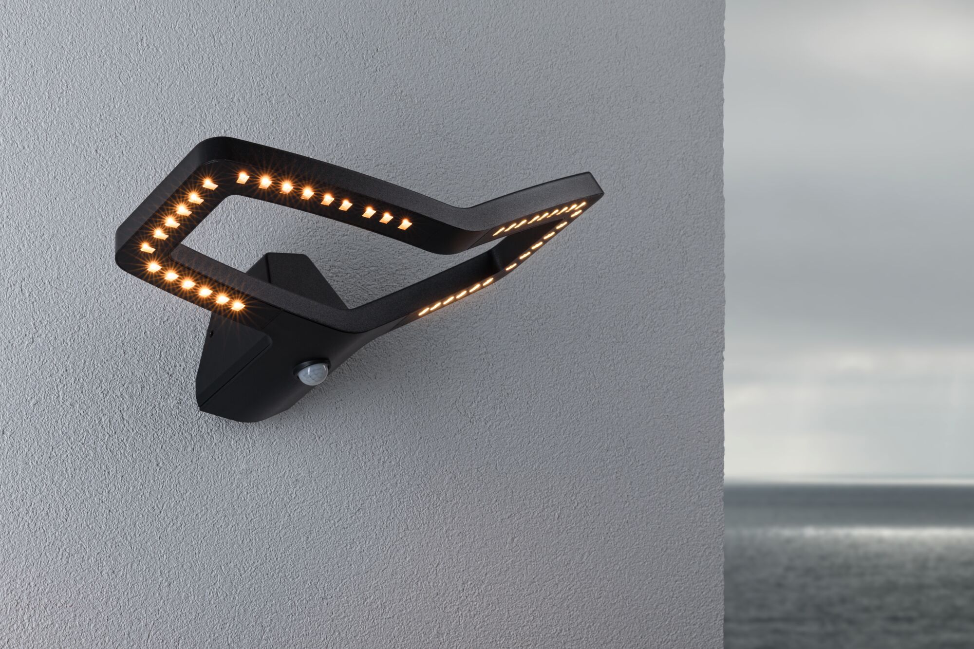 Zwarte LED-wandlamp met modern ontwerp en bewegingssensor op grijze muur met zeezicht