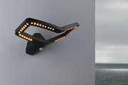 Black LED wall light with modern design and motion sensor on grey wall overlooking the sea