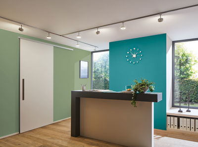 Moderne grijze balie voor een turquoise muur met minimalistische klok en houten vloer in kantoor