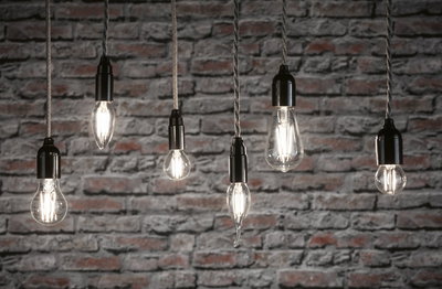 Sechs klare Filament-LED-Leuchtmittel in verschiedenen Formen vor grauer Backsteinwand für dekorative Beleuchtung