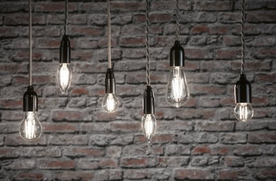 Sechs klare Filament-LED-Leuchtmittel in verschiedenen Formen vor grauer Backsteinwand für dekorative Beleuchtung