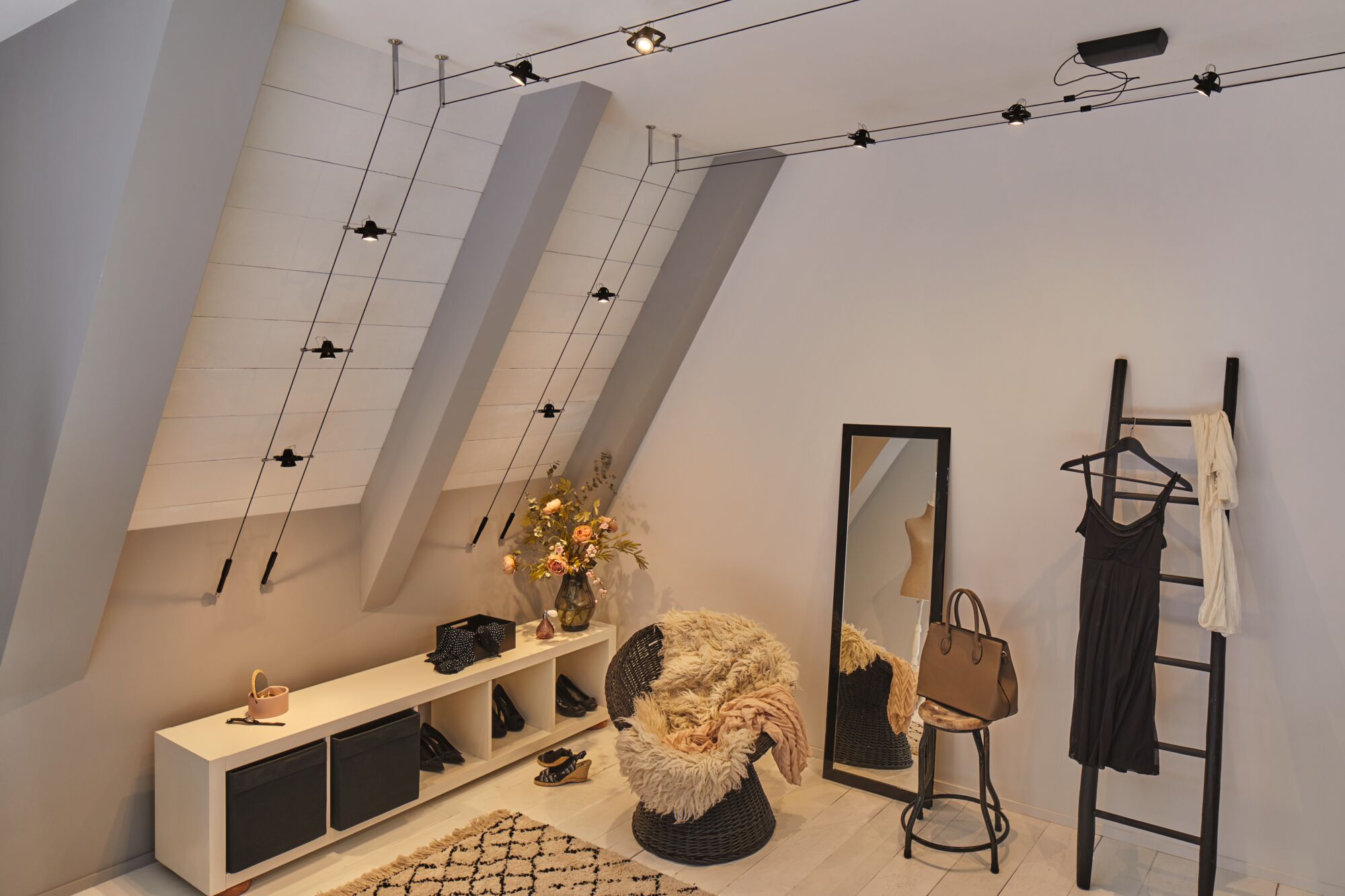 Dressing moderne avec éclairage de plafond noir sur câble et fauteuil confortable avec couverture en fourrure