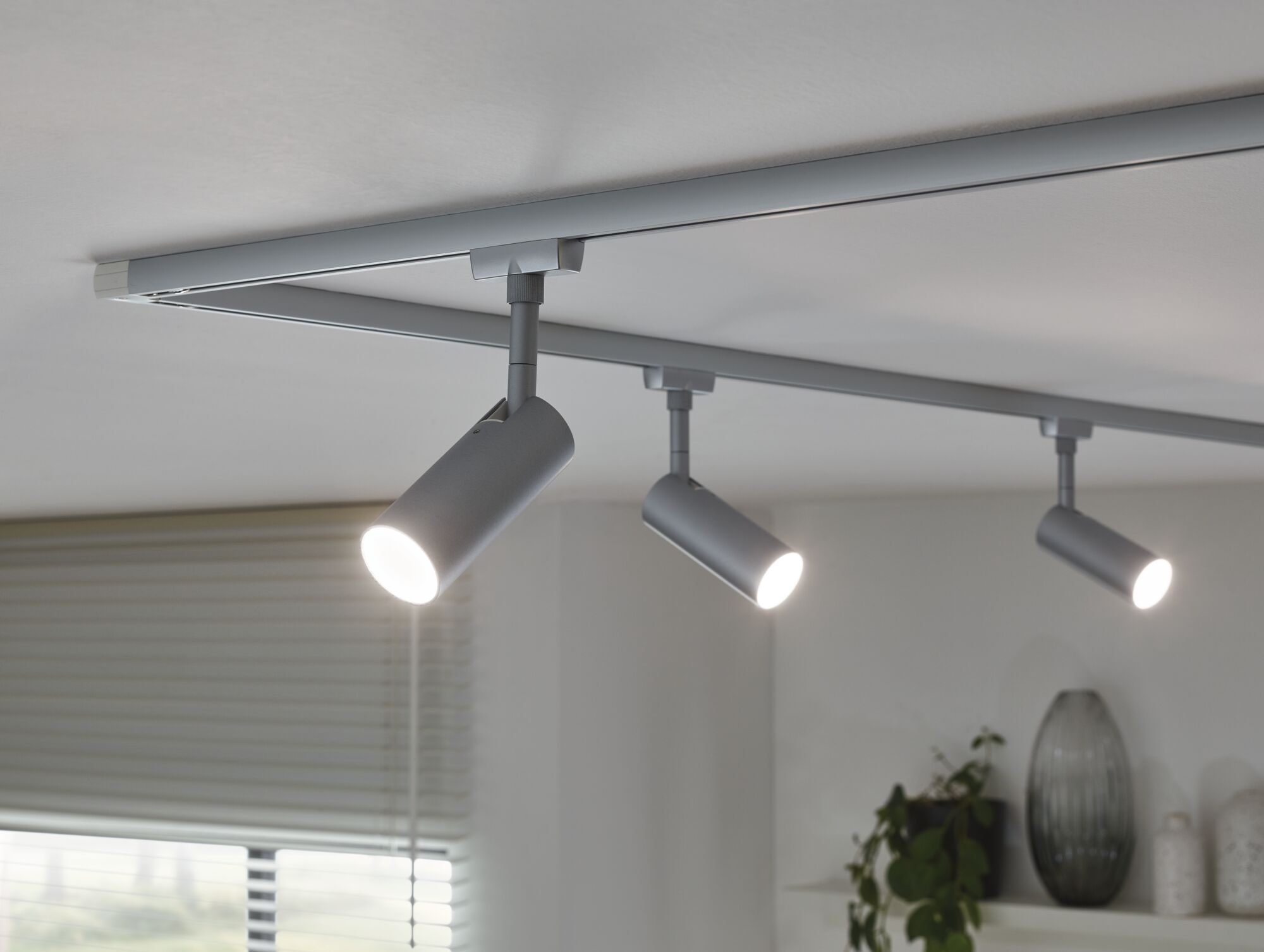 Three silver LED track spotlights on white ceiling for modern home lighting.
