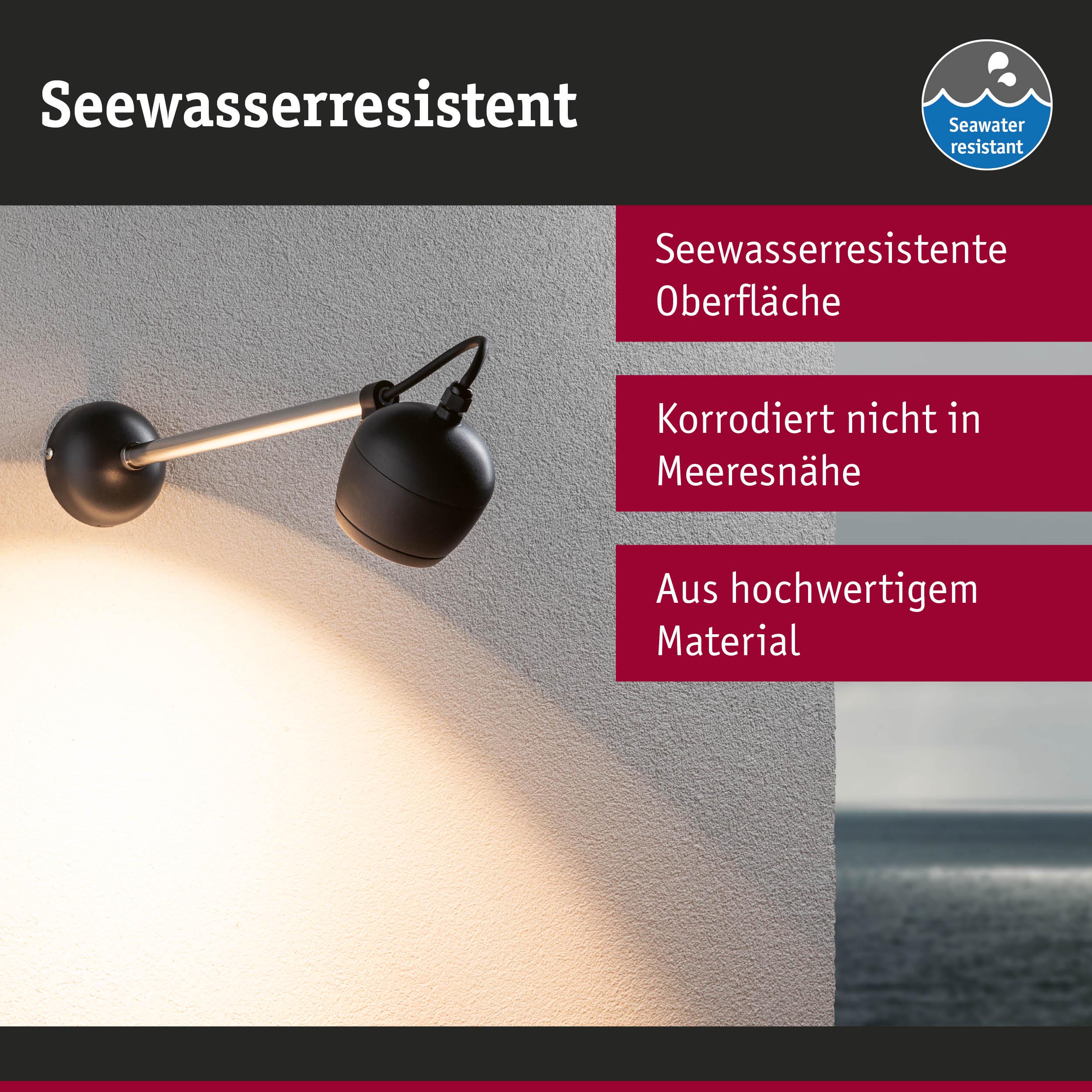 Schwarze, seewasserresistente Wandlampe aus hochwertigem Material mit warmem Licht an weißer Wand