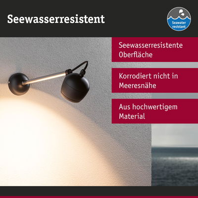 Schwarze, seewasserresistente Wandlampe aus hochwertigem Material mit warmem Licht an weißer Wand