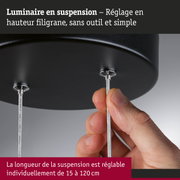 Main ajustant la fixation métallique noire d'un luminaire suspendu réglable en hauteur avec câble en acier