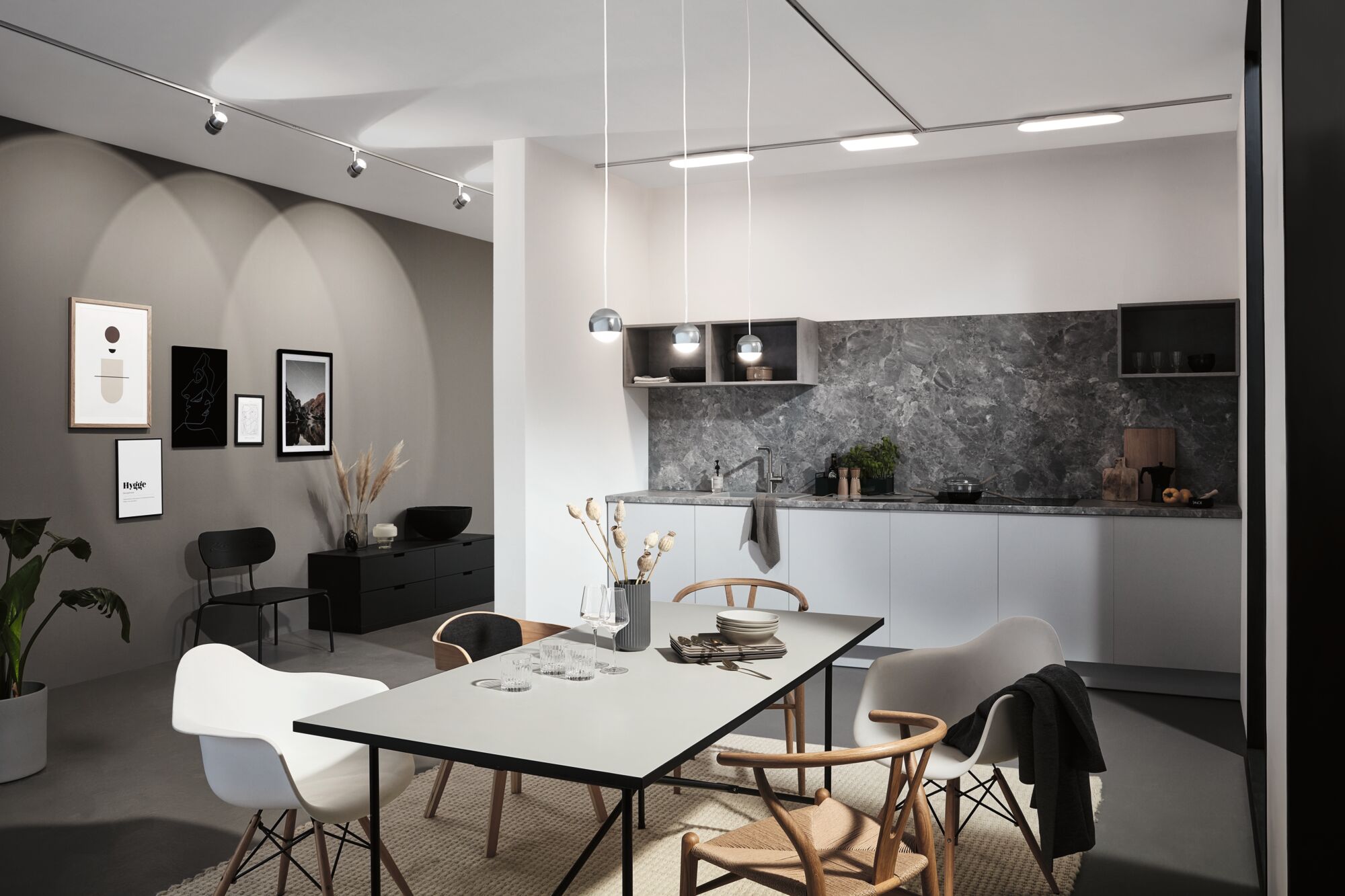 Modern kitchen with grey marble backsplash, white cabinets, and minimalist pendant dining lights.