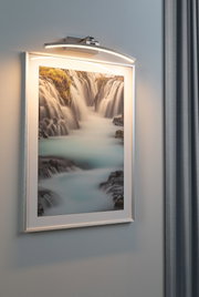Moderner LED-Bilderleuchter in gebürstetem Aluminium mit warmweißem Licht an grauer Wand.