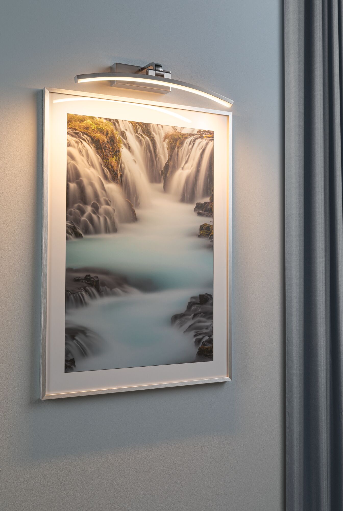 Moderner LED-Bilderleuchter in gebürstetem Aluminium mit warmweißem Licht an grauer Wand.