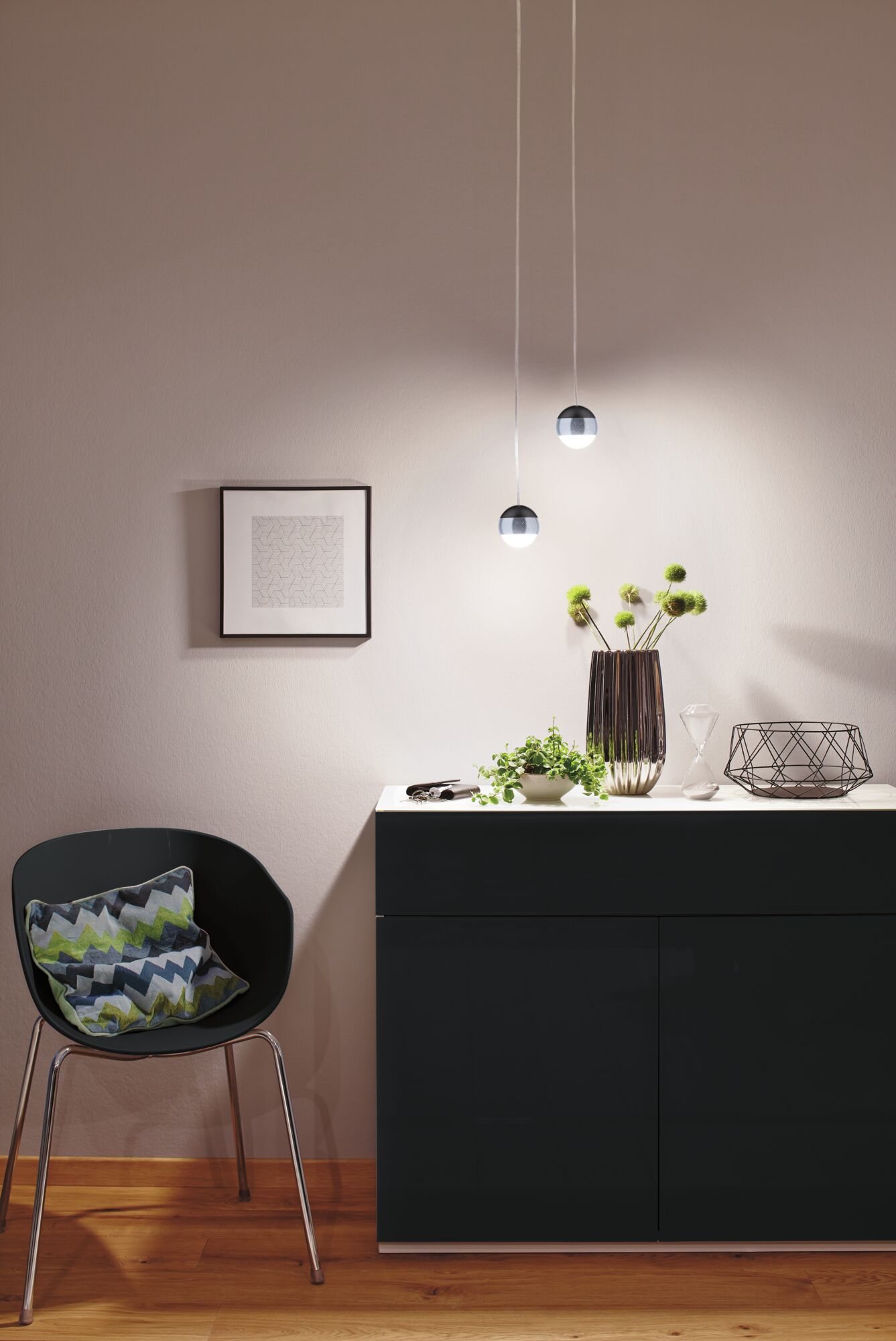 Moderne Pendelleuchten mit runden schwarzen Metallkugeln über schwarzem Sideboard in Wohnraum.