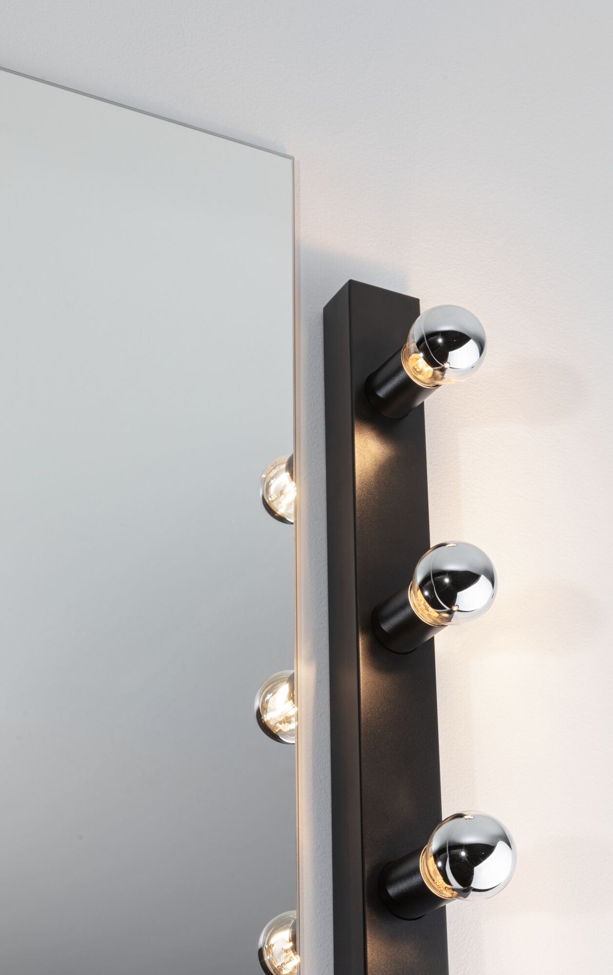 Schwarze Wandlampe mit sechs runden Glühbirnen neben Spiegel, moderne LED-Spiegelleuchte.