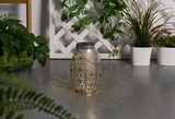 Metal lantern with intricate pattern casting warm light, decorative for indoor and outdoor use.