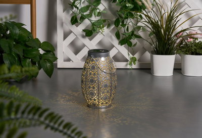 Metal lantern with intricate pattern and warm light, decorative for garden or patio lighting
