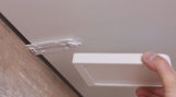 Main tenant un cadre carré blanc de panneau LED près d’un support de plafond en plastique pour installation LED