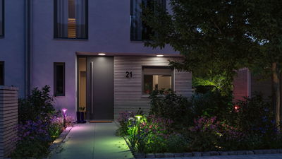 Moderne huisentree met grijze deur en kleurrijke LED-tuinverlichting voor sfeervolle buitenverlichting