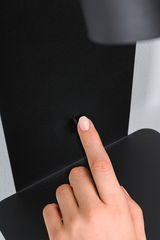 Hand pressing small black switch on matte black metal panel for lighting control